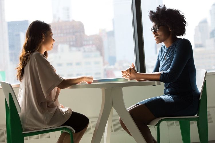 Image of two women talking while sitting at a table