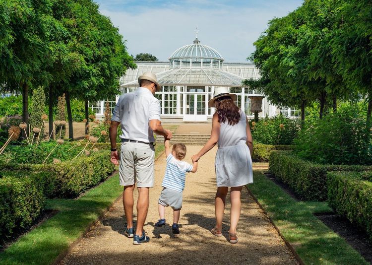 Image of a husband and wife holding hands with their son walking around a park