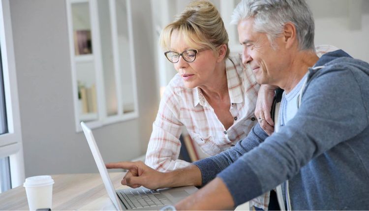 An image of an older couple looking at the screen of a laptop
