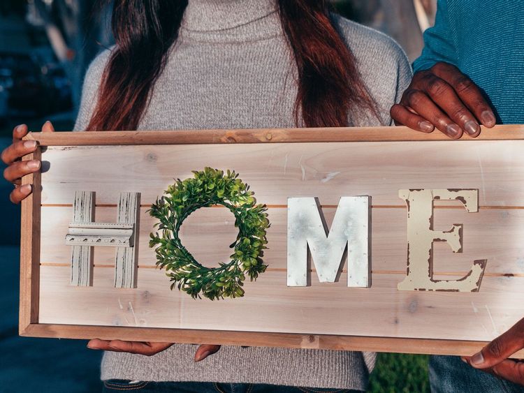Image of a couple holding a sign that says 'home'.