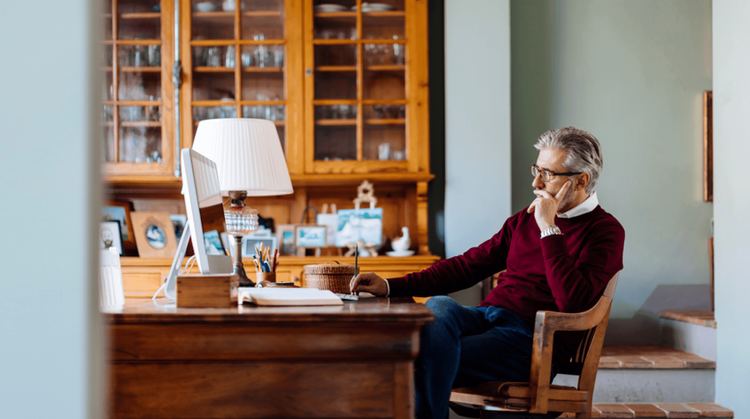 Image of a man looking at a computer in deep thought.
