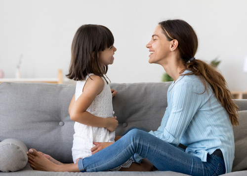 Image depicting a mother laughing on a couch with her daughter