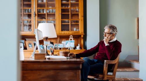 Image of a man looking at a computer in deep thought.